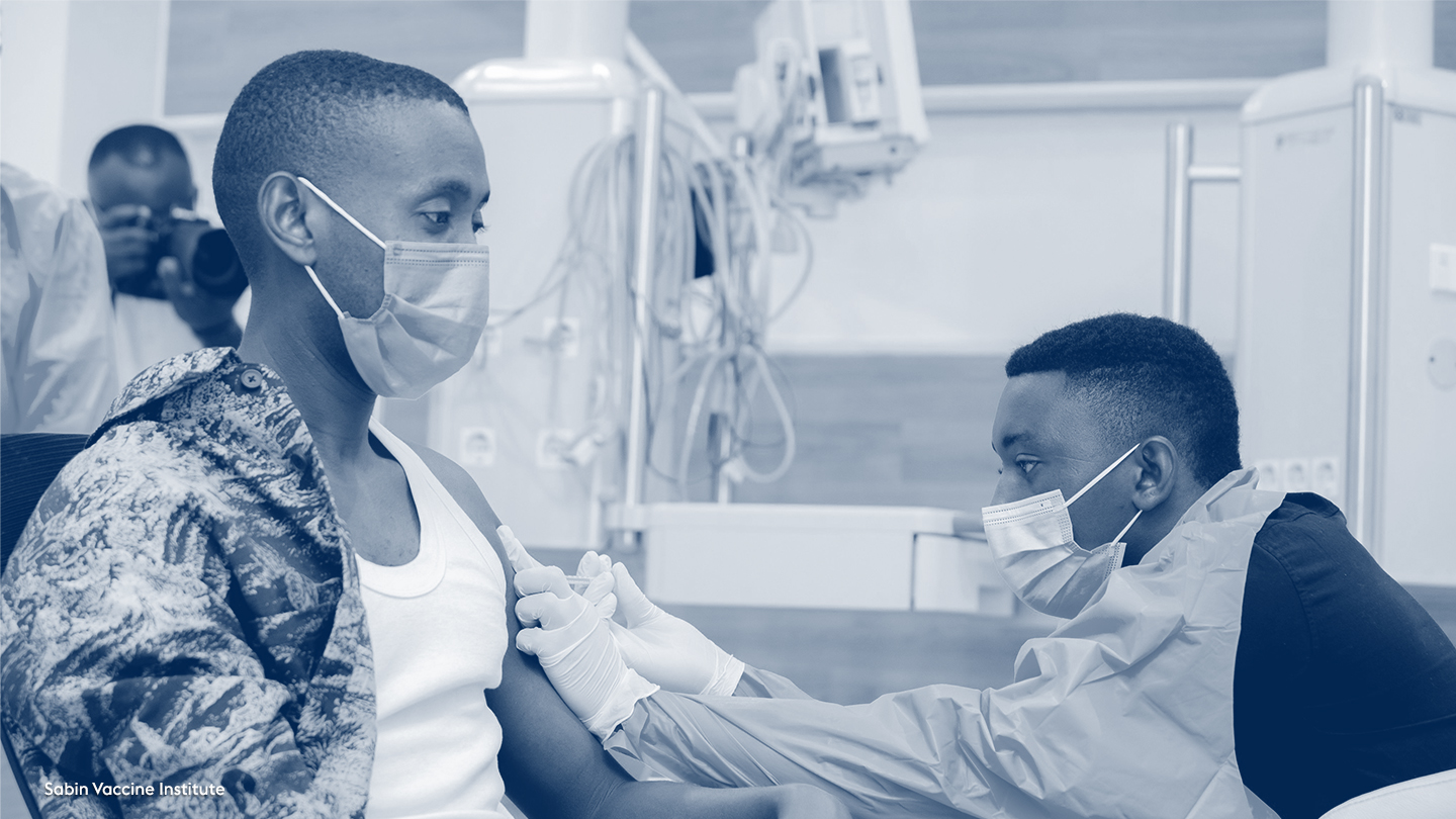 man sat down receiving vaccine from healthworker in PPE