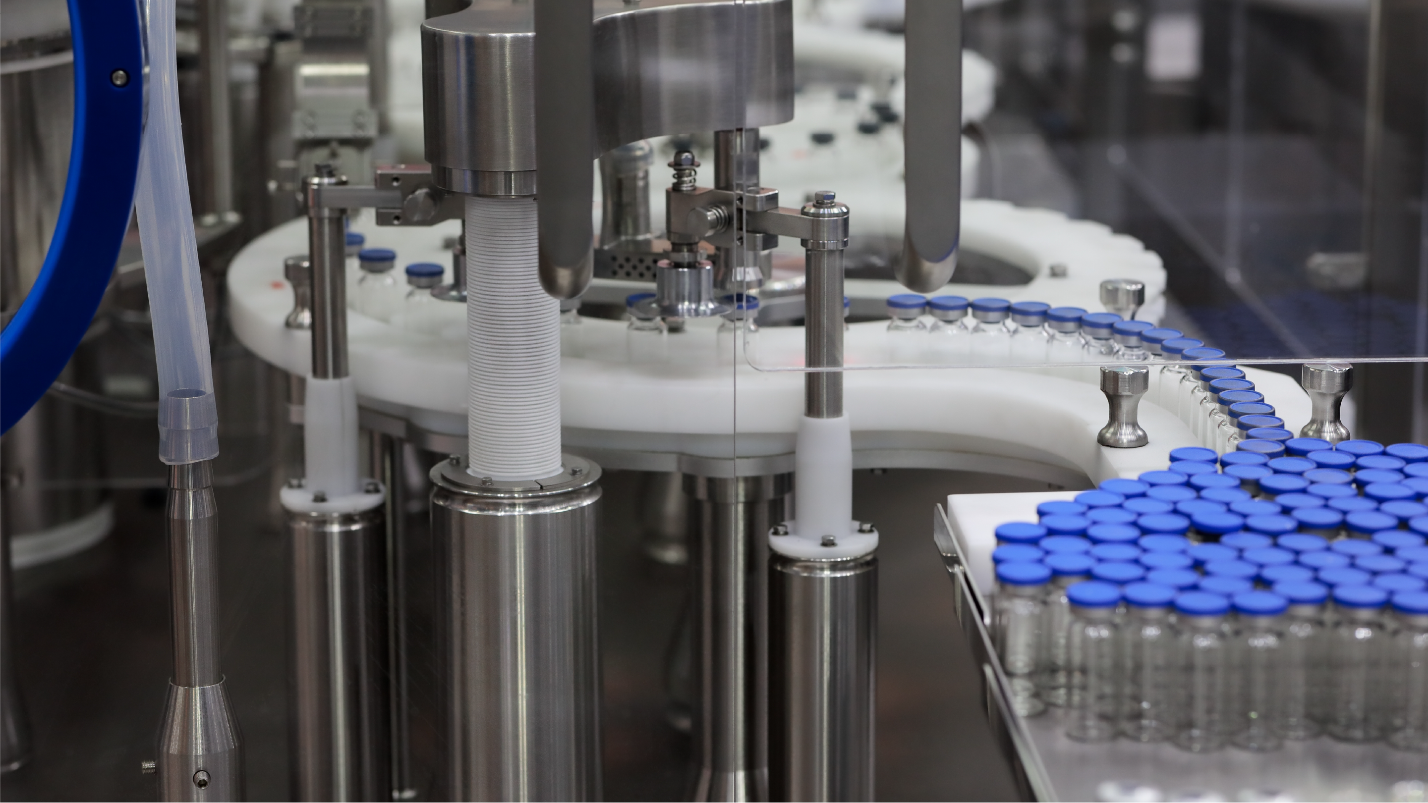 closeup showing blue lidded glass vials on a conveyer belt