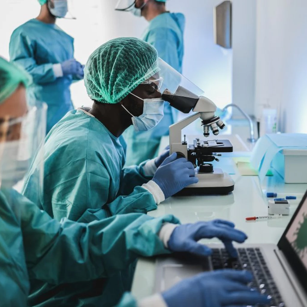 Scientists in lab with microscope and laptop 