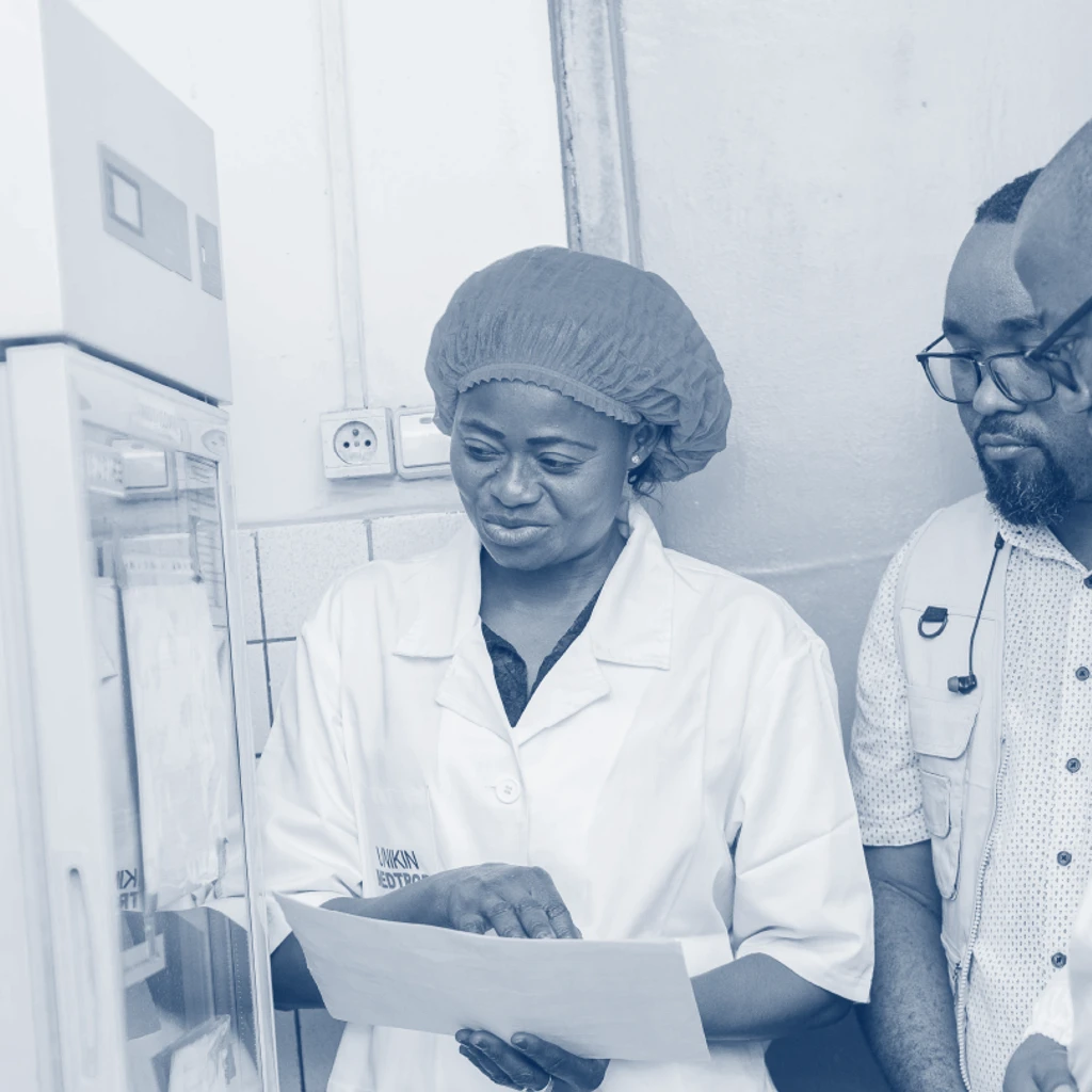 Three researchers from University of Kinshasa looking at paper by lab machine