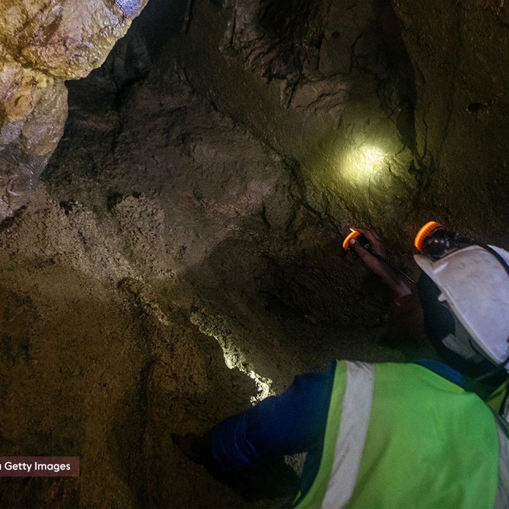 miners in a tunnel with head torchers looking up in a cave