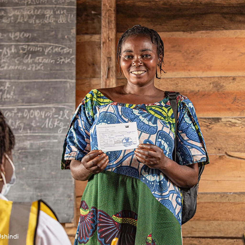 Sauda, a mother of seven, proudly displays her vaccination card after receiving her mpox vaccine at Kabingo Primary School in the Karisimbi health zone, near Goma, in North Kivu province, DR Congo, on 26 March 2025.