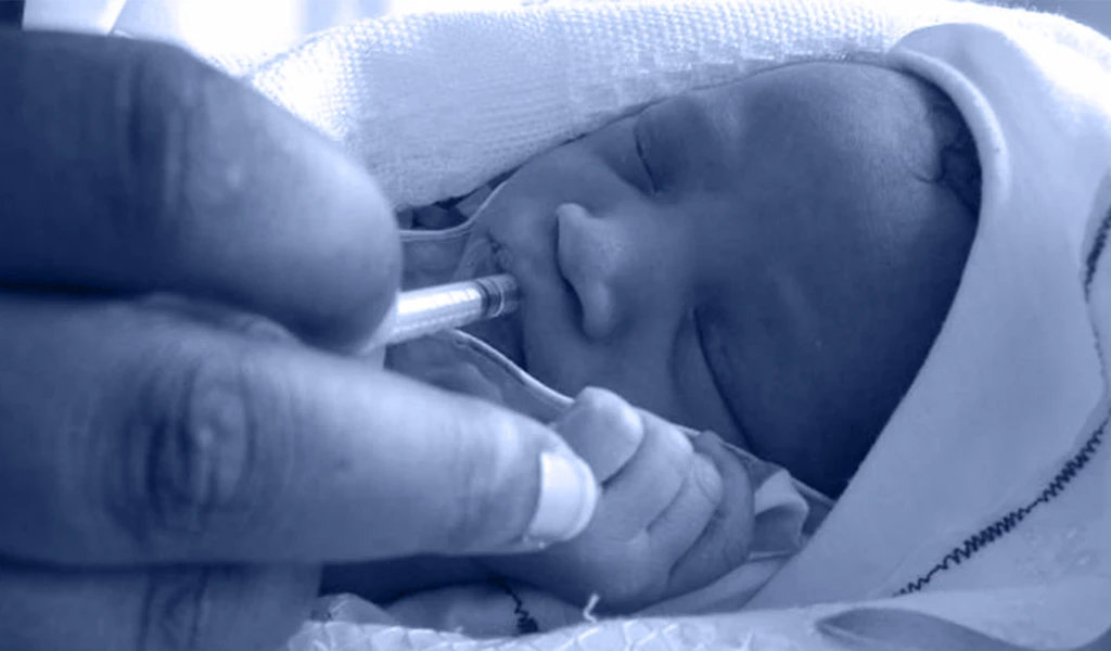 closeup of new-born baby receiving oral medication