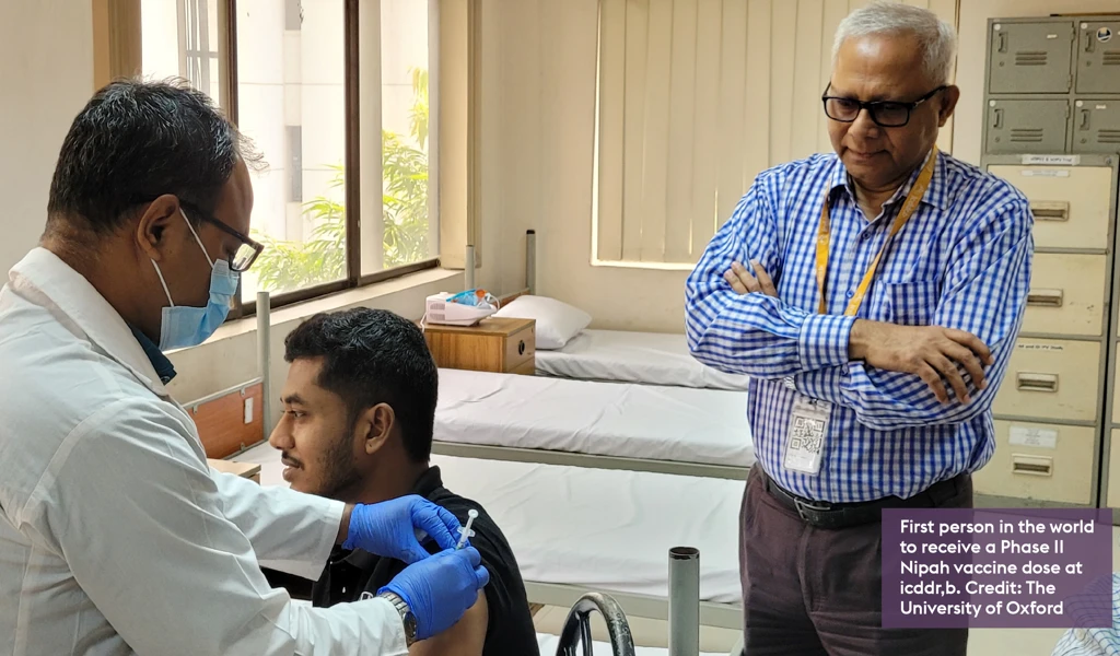 photo of person sat down receiving Nipah vaccine by health worker