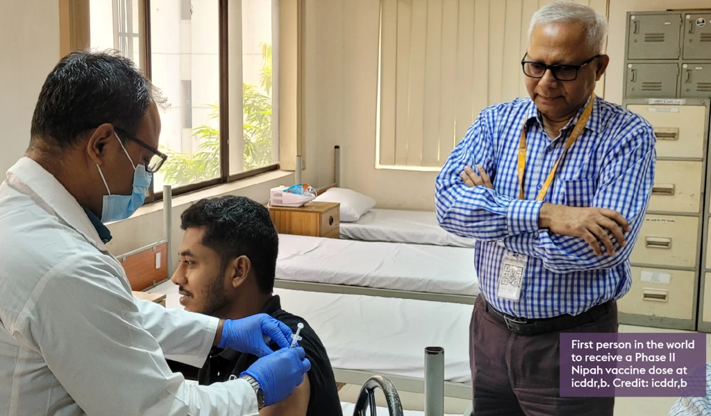 photo of person sat down receiving Nipah vaccine by health worker