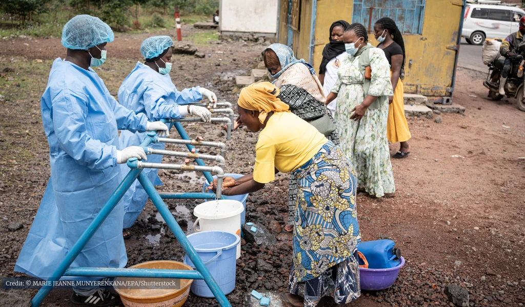 women outside washing their hands under taps