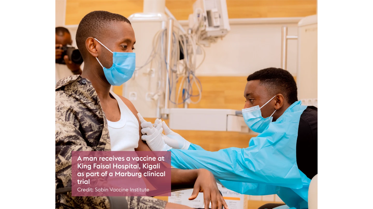 man sitting down getting vaccination from health worker in PPE