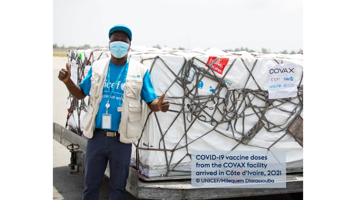Man at airport next to a large crate containing boxes of vaccines