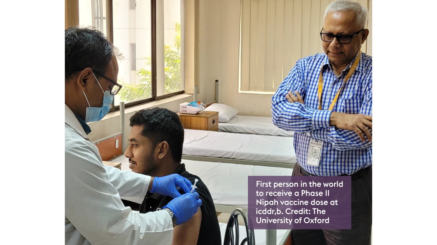 photo of person sat down receiving Nipah vaccine by health worker