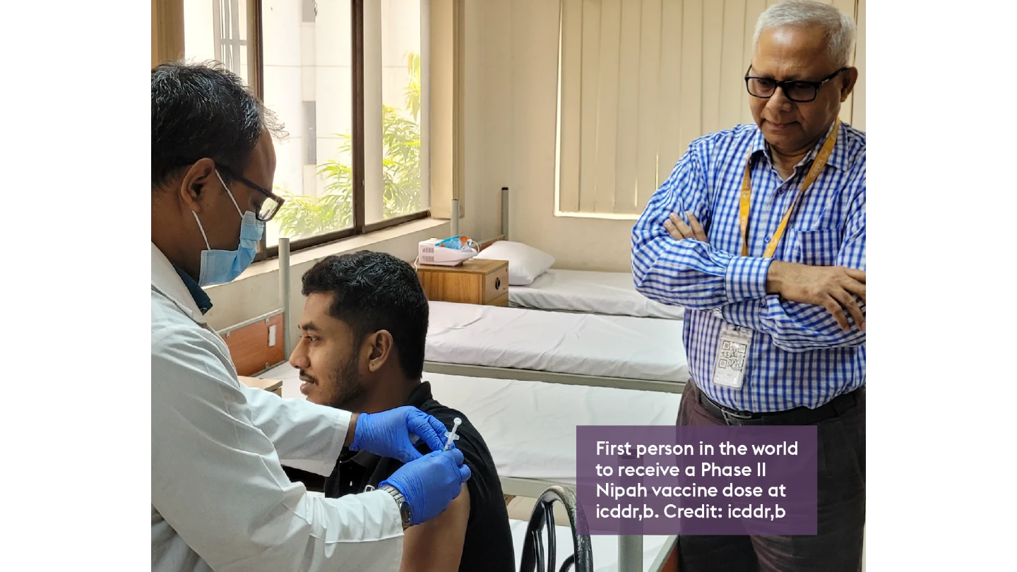 photo of person sat down receiving Nipah vaccine by health worker