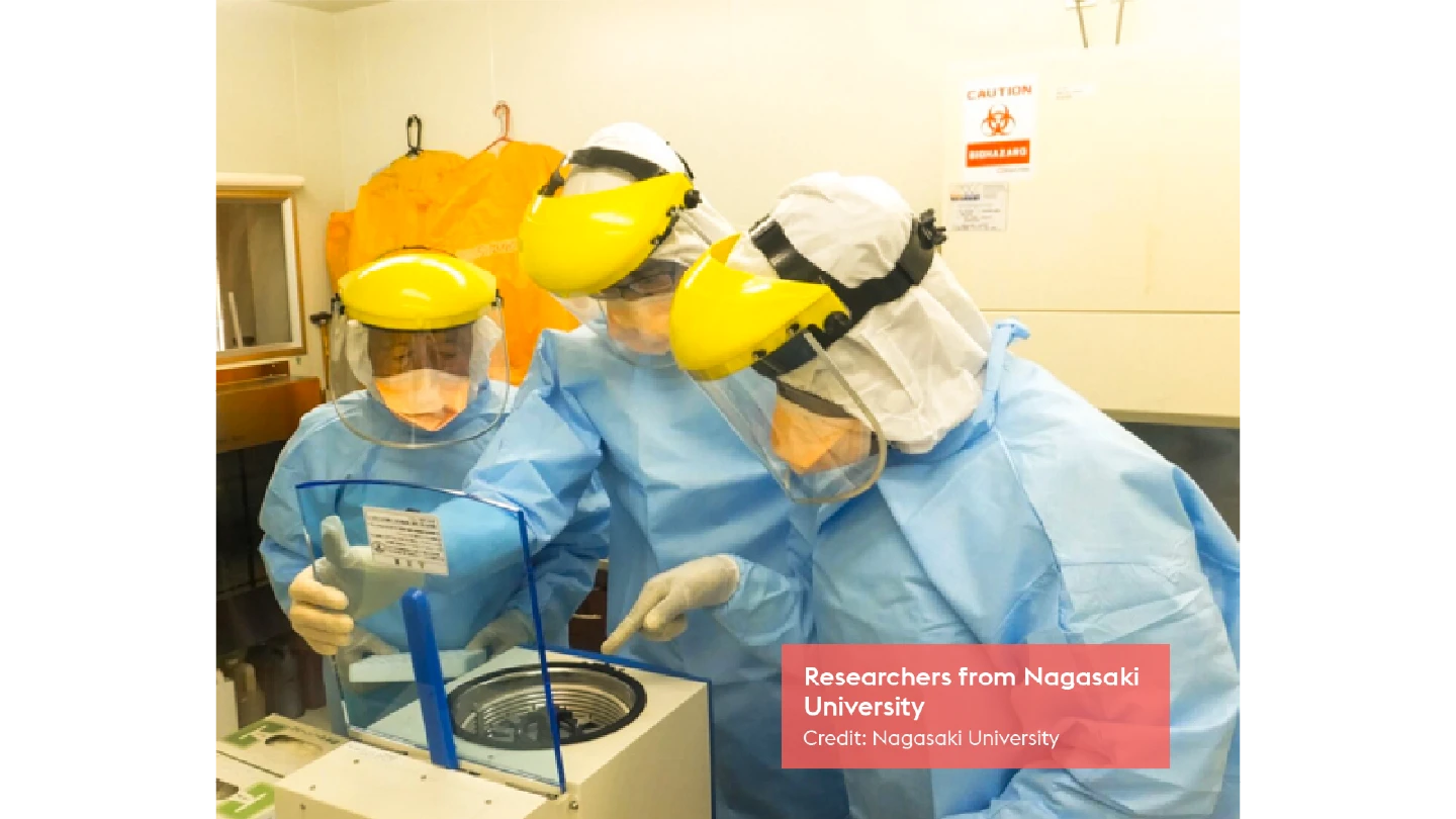 three researchers in full PPE using lab equipment
