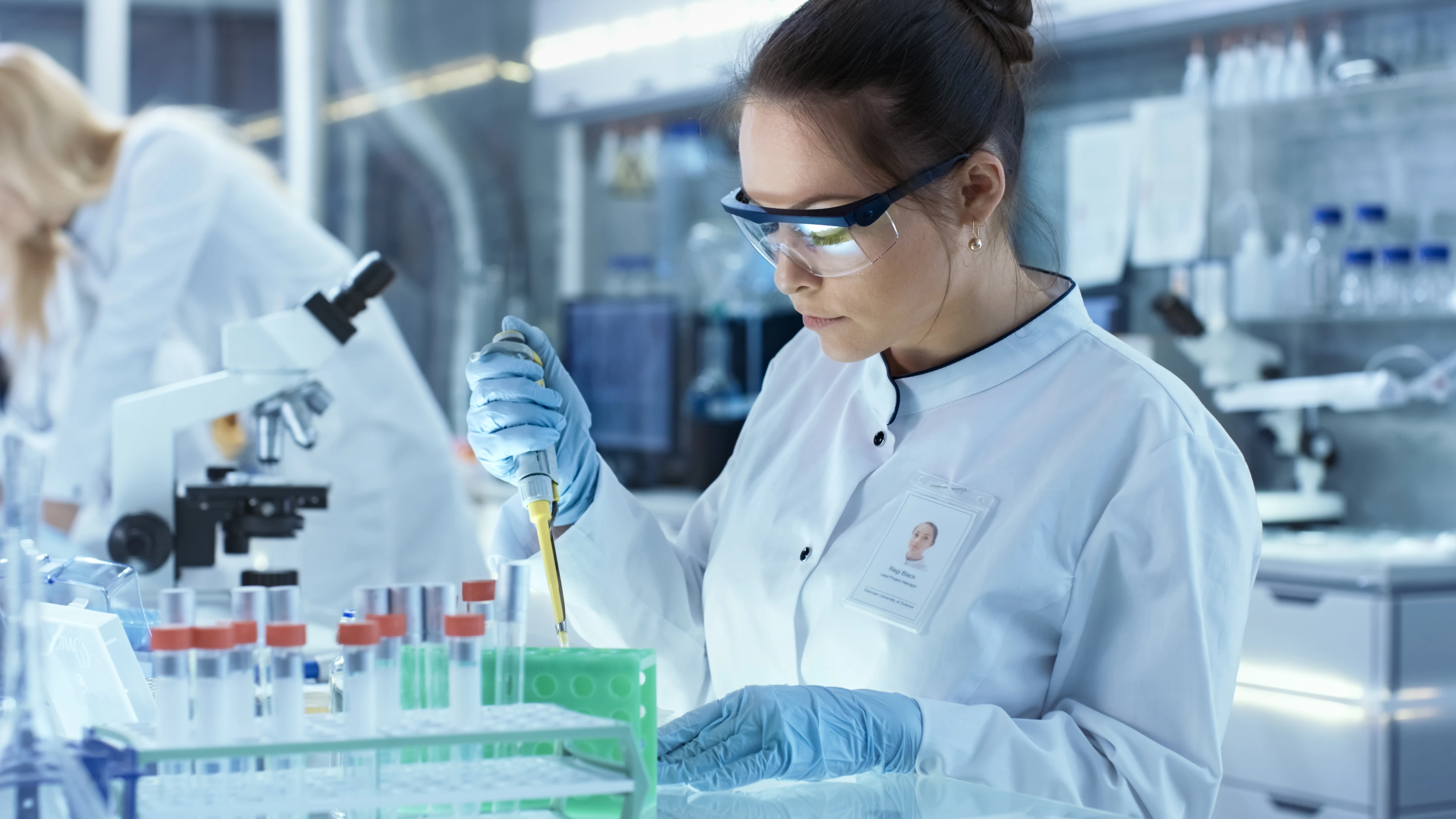 Female Research Scientist Uses Micropipette Filling Test Tubes in a Big Modern Laboratory.