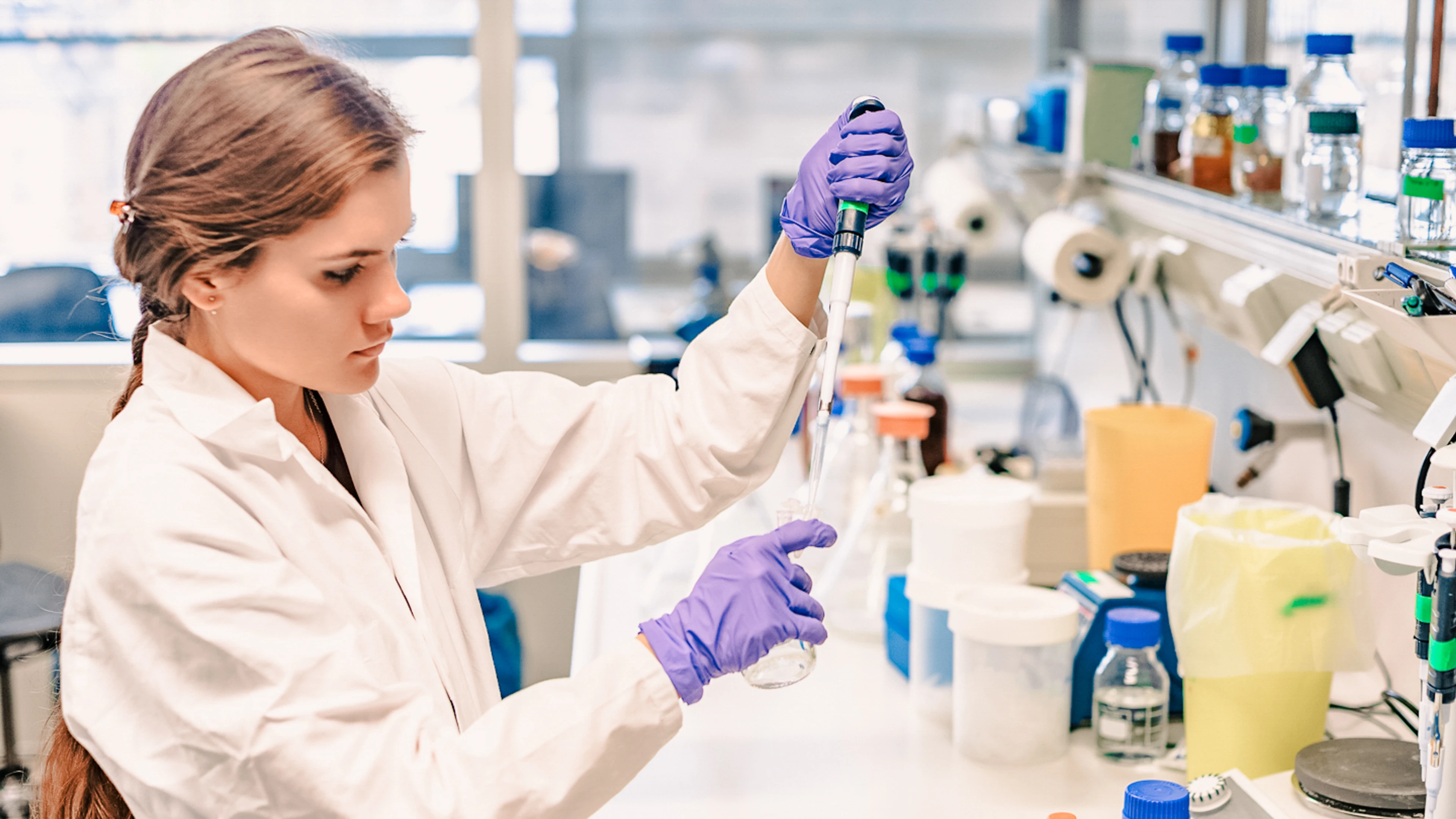 female researcher holding pipette and vial working in lab