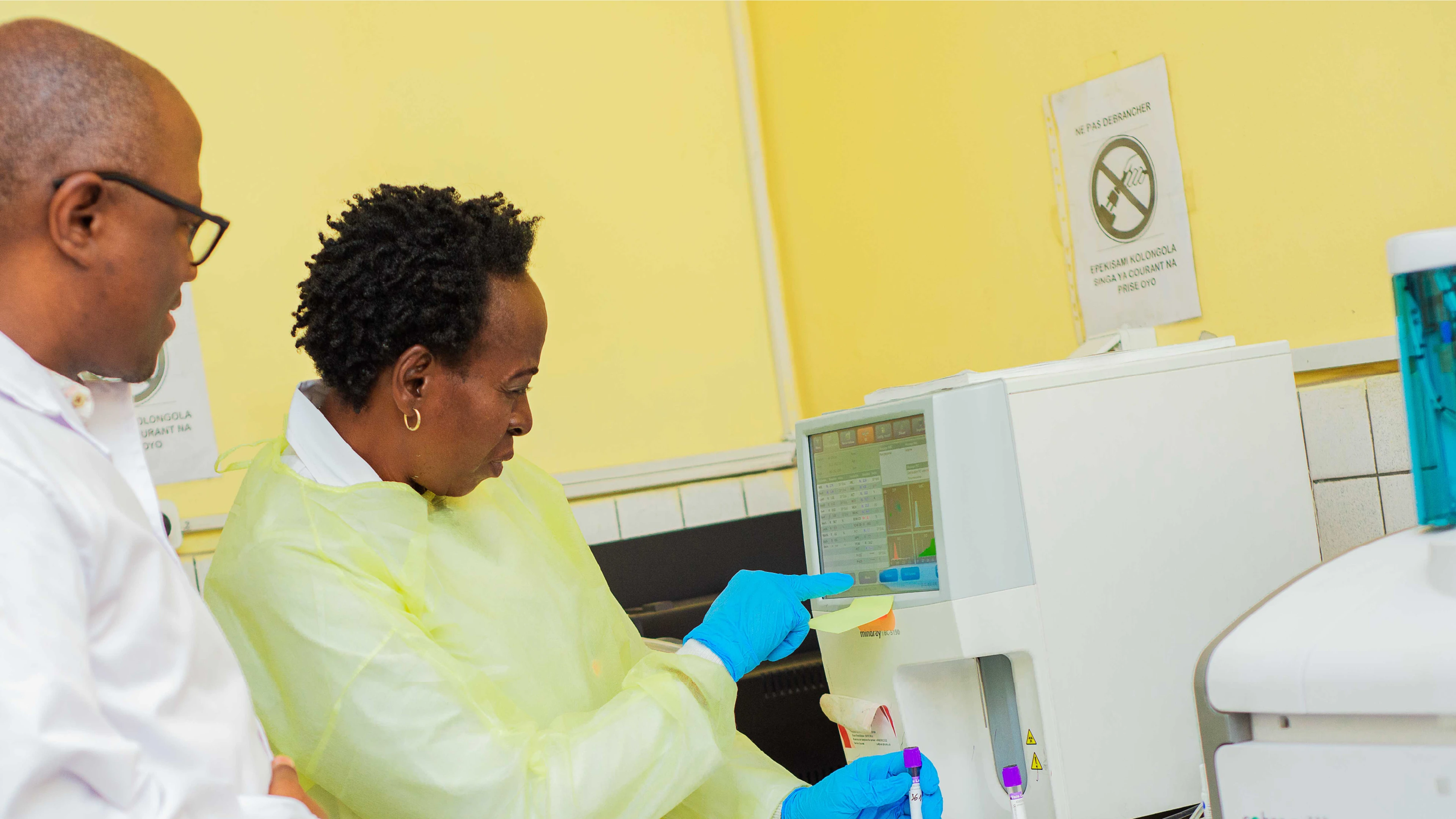 two scientists in PPE looking at equipment