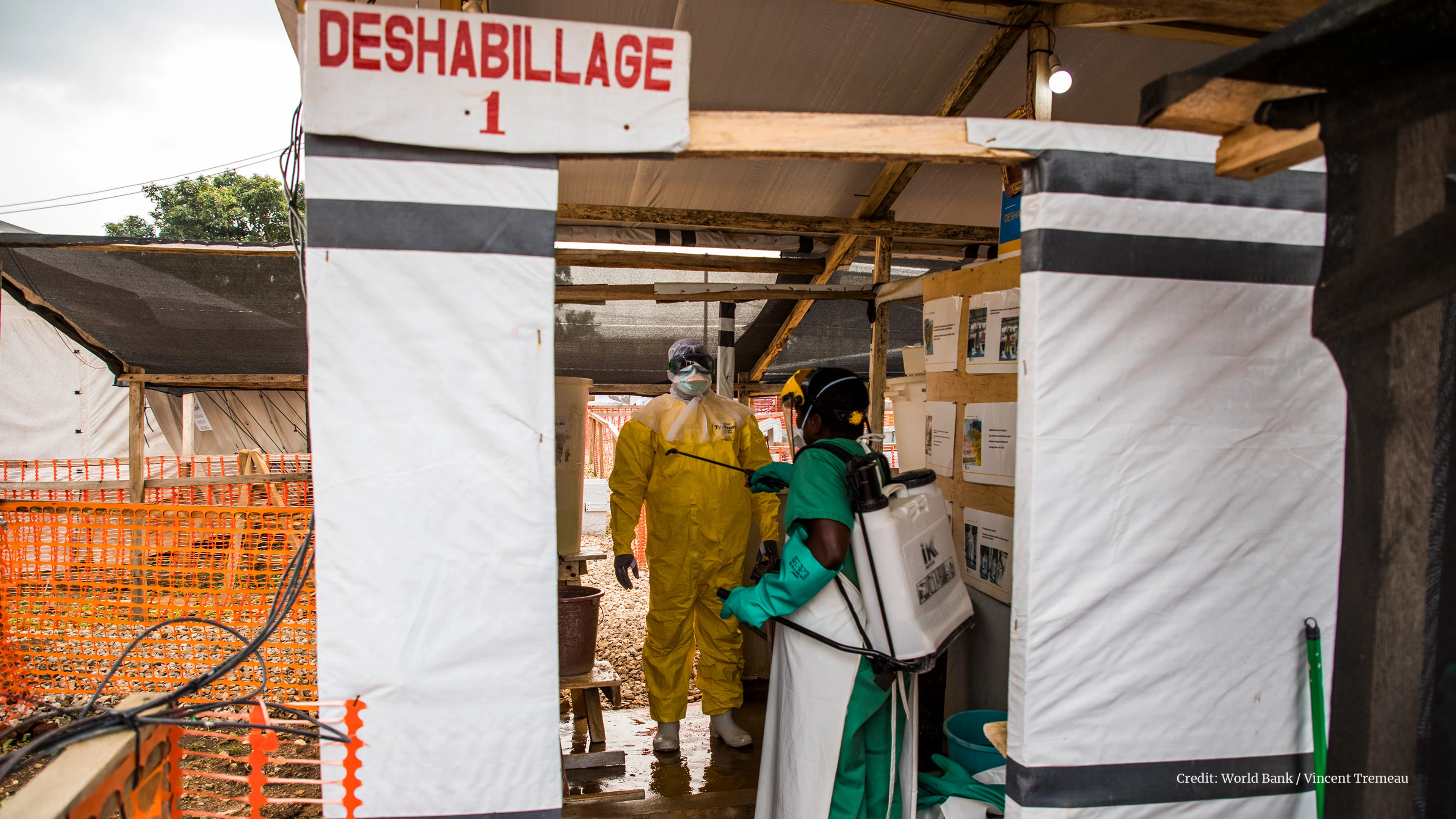 Doctor in full PPE gets disinfected in outdoor area by colleague