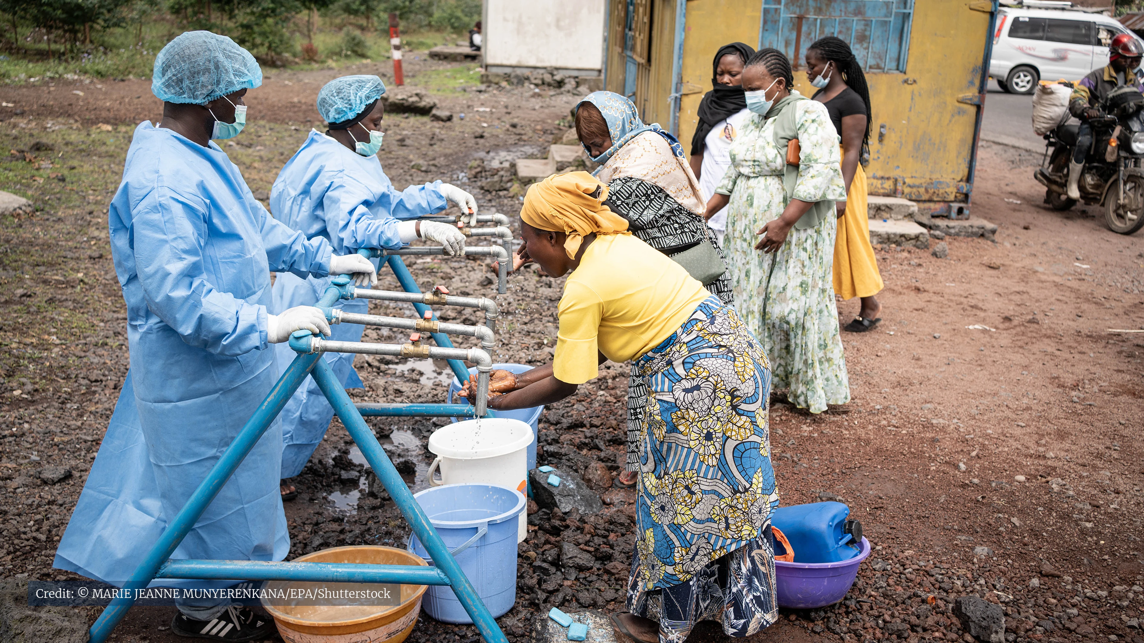 women outside washing their hands under taps